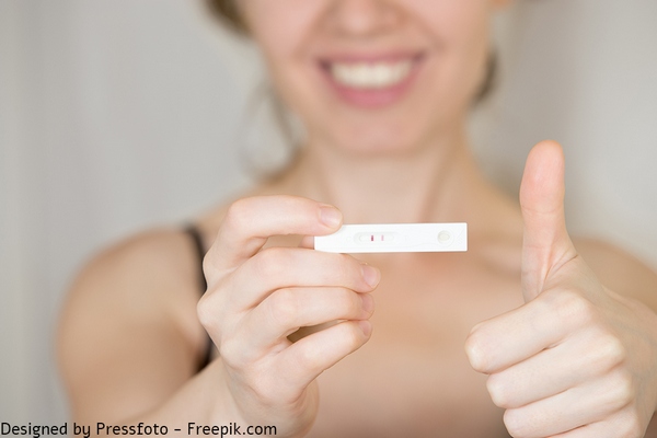 אישה מחזיקה בדיקת הריון חיובית. מזל טוב! הגיע הזמן להתחיל מעקב הריון, אם לא התחלת עוד לפני ההריון
